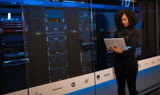 Vrouw met laptop naast glazen serverwand 2
