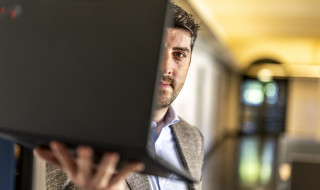 Raoul Winkens met een laptop voor zijn gezicht