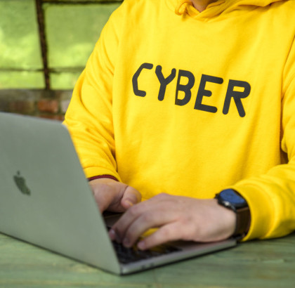 Man in yellow jersey with CYBER on it behind laptop