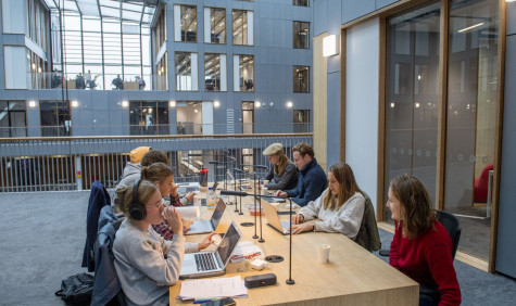 Studenten met laptops aan een gezamenlijke tafel in een instelling