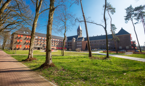 Gebouw van een universiteit in Nederland met op de voorgrond bomen