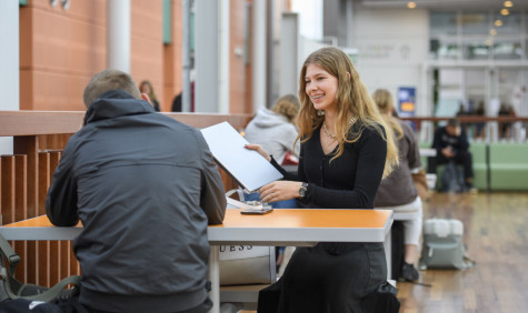 studente in gesprek met medestudent aan tafel