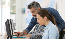 Man en vrouw achter de computer, man wijst iets aan op het scherm