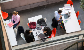 studenten zitten in een ruimte op rode stoelen