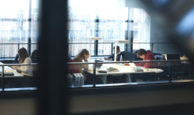 Studenten achter laptops aan leestafels vanuit de verte