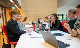 6 studenten werken in de bibliotheek samen aan een tafel