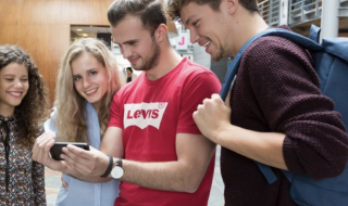 Vier studenten kijkend naar een mobiele telefoon