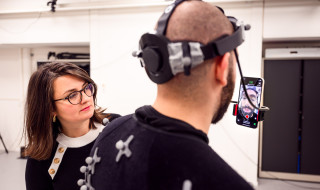Zerrin Yumak in the motion capture lab and an actor with a headset with a mobile phone attached to it on which he can see his facial expression