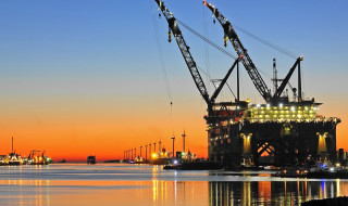 Foto in de haven van Rotterdam met een groot vrachtschip bij zonsondergang