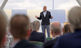 Marcel Levi staat op het podium als spreker voor een publiek