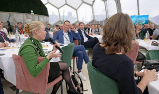 Een vrouw aan een tafel spreekt via een microfoon