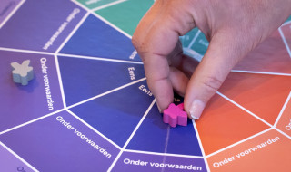 Een hand houdt een pion bij het publieke waarden spel