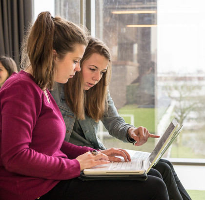 Twee studentes kijken samen naar een laptop