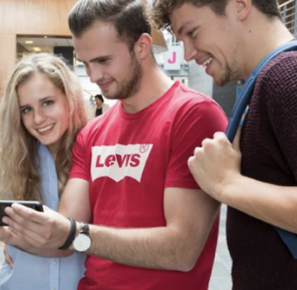 Vier studenten kijkend naar een mobiele telefoon