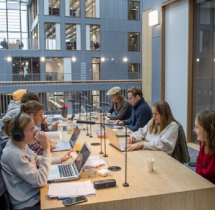 Studenten met laptops aan een gezamenlijke tafel in een instelling