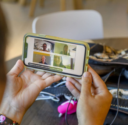 Student kijkt op het beeldscherm naar een videogesprek met meerdere deelnemers