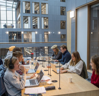 Studenten met laptops aan een gezamenlijke tafel in een instelling